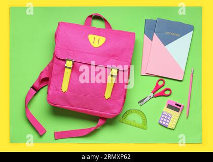Stylischer Schulrucksack mit verschiedenen Schreibwaren auf farbigem Hintergrund Stockfoto