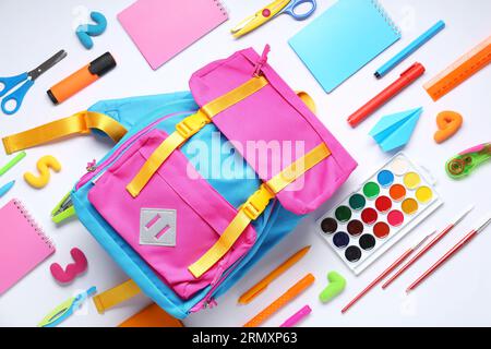 Stylischer Schulrucksack und verschiedene Schreibwaren auf weißem Hintergrund Stockfoto
