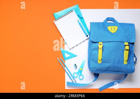Stylischer Schulrucksack mit verschiedenen Schreibwaren auf farbigem Hintergrund Stockfoto