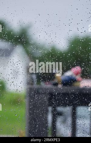 Blick nach draußen an einem regnerischen Tag mit Wassertropfen am Fenster. Stockfoto