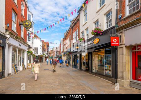 Geschäfte, Straßencafés und Pubs säumen das Haupteinkaufsviertel der High Street in der mittelalterlichen historischen Stadt Winchester, England, Großbritannien. Stockfoto