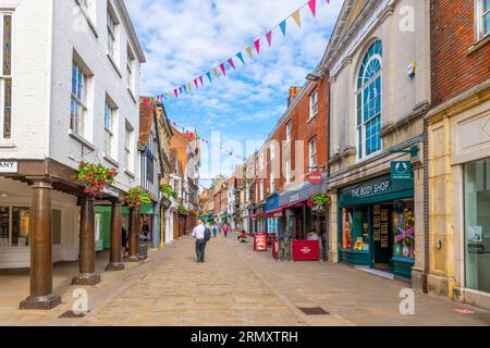 Geschäfte, Straßencafés und Pubs säumen das Haupteinkaufsviertel der High Street in der mittelalterlichen historischen Stadt Winchester, England, Großbritannien. Stockfoto