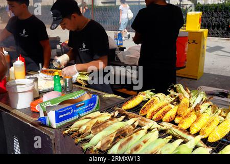 Die Maiz Factory Con Amor de Ecuador-Mitarbeiterin bereitet auf einer Straßenmesse in New York City, 26. August 2023, gegrillten Mais vom Choclo Asado, Elote, auf dem Maiskolben zu Stockfoto