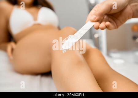 Frau mit Haarentfernung am Bein mit Wachs oder Zucker-Enthaarung im Schönheitssalon Stockfoto
