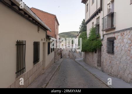 Eine schmale Kopfsteinpflasterstraße in der Stadt Pastrana bei Sonnenuntergang in Alcarria, Guadalajara, Spanien Stockfoto