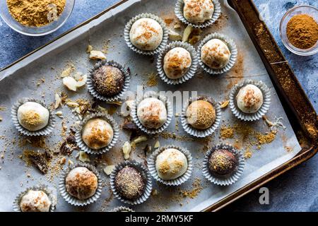 Kürbis-Gewürztrüffel in Pappbechern auf einem unordentlichen Backblech aus Pergamentpapier. Stockfoto