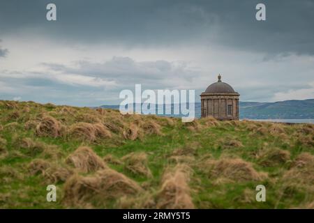 Mussenden-Tempel im Norden irlands bei Demesne bergab an einem bewölkten Tag, der sich zwischen dem Gras versteckt. Wunderschönes Mausoleum in der irischen Landschaft. Stockfoto