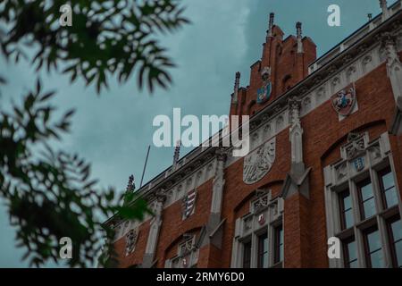 Jagielonski-Universität in krakau, Außenansicht des Backsteinhauses im Zentrum an einem Sommertag. Sichtbare Bäume und rotes Backsteinhaus. Stockfoto