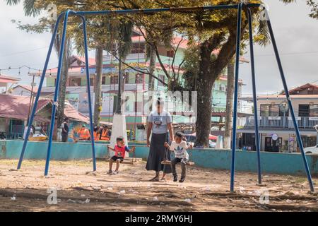 Bocas del Toro, Panama, 3,5.2023: Kinder und Mutter spielen an einem heißen Sommertag in einem Park auf dem Hauptplatz der Stadt Bocas. Stockfoto