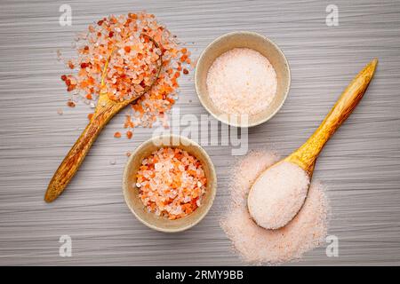 Ein flaches Lagenfoto von grobem und feinem Himalaya-rosa Salz in Schüsseln und auf Löffeln. Stockfoto