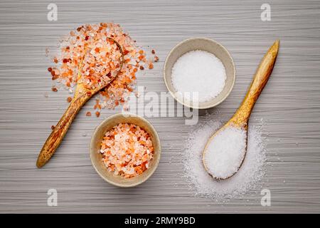 Ein flaches Lagenfoto os grobes Himalaya rosa Salz und grobes weißes Meersalz in Schüsseln und auf Holzlöffeln. Stockfoto