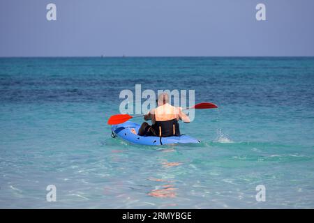 Kajakfahren im Meer, Mann mit Schwimmweste, der mit dem Paddel im Kanu sitzt. Reise- und Wassersportkonzept Stockfoto