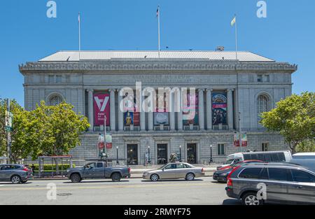 San Francisco, CA, USA - 12. Juli 2023: Autoverkehr vor der Fassade des Asian Art Museum mit seinen Säulen und bunten Bannern, die seine Trea propagieren Stockfoto