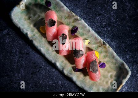 Über dem langen Teller mit Sushi-Set aus Thunfisch, dekoriert mit Trüffeln bei schwachem Licht Stockfoto