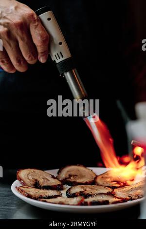 Stock Foto von unerkannten Koch mit Küchenbrenner im Restaurant. Stockfoto