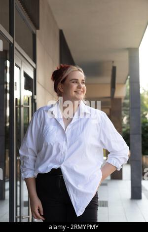 Portrait Junge pensive träumende glückliche Frau 20er Jahre in lässiger Kleidung, die in der Sommerstadt draußen lächelt, sieht beiseite. Aktiv, Selbstbewusst, Urban Stockfoto