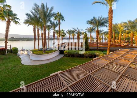 Blick auf die Wüste und Hügel durch Palmen entlang des Nils in einem Luxusresort in der ägyptischen Stadt Luxor, Ägypten. Stockfoto