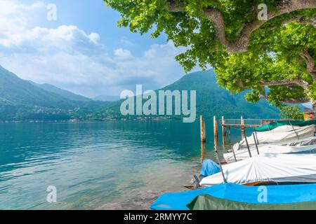 Überdachte Boote fuhren am Ufer des Luganer Sees, umgeben von Bergen in der latianischen Provinz Lombary. Stockfoto