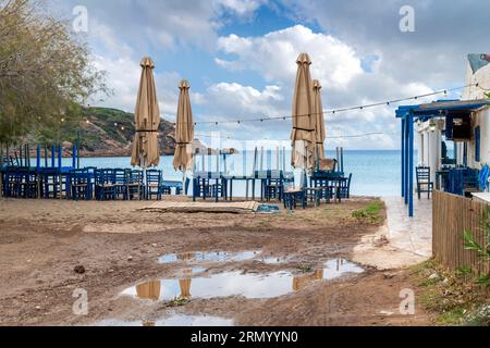 Ein geschlossenes Café am Meer mit blauen Tischen und Stühlen, an einem verregneten Herbsttag entlang der Küste von Kap Sounion, Griechenland. Stockfoto