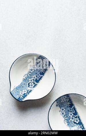 Weiß-blaue Tempura-Soße-Schüssel mit Blumenmuster, handbemalte minimalistische Soße-Schüssel, japanisches Geschirr auf minimalistischem Hintergrund Stockfoto