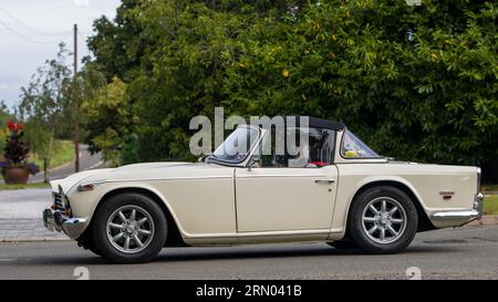 Whittlebury, Northants, UK - 27. August 2023: 1968 weißes Triumph TR5 Auto, das auf einer englischen Landstraße fährt Stockfoto