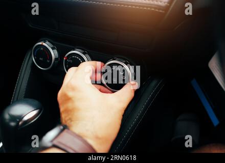 Der Fahrer stellt den Windrichtungsschalter auf dem Armaturenbrett der Klimaanlage ein. Stockfoto