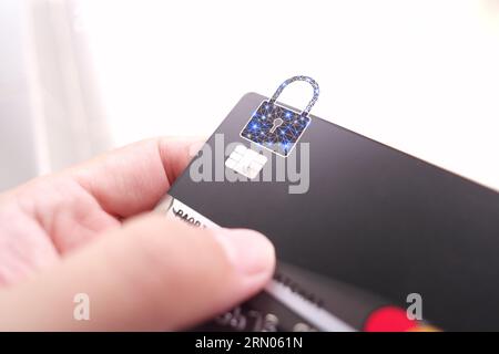 Nahaufnahme von Mann Hand mit Kredit- oder Debitkarte mit Vorhängeschloss, schwarze Kreditkarte mit Schutz von Finanztransaktionen. Stockfoto