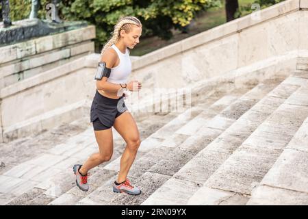 Junge sportliche Frau, die Sport treibt und die Treppe rauf läuft. Stockfoto
