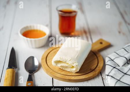 Nahaufnahme eines Bildes von weißer cremeweißer Milch-Kajak-Butterrolle, die mit Tee auf einem Holzteller gegossen wird Stockfoto