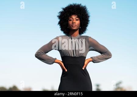 Schöne afroamerikanische Frau posiert, läuft und modelt in enger Kleidung im Outdoor-Park an sonnigen Tagen Stockfoto