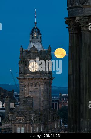 Edinburgh, Schottland, Großbritannien, 31. August. Wetter in Großbritannien: Vollblauer Supermond. Der Vollsupermond setzt über die ikonische Skyline der Stadt mit dem Balmoral-Uhrenturm, der eine Zeit von 6 Uhr zeigt, die von Calton Hill aus gesehen wird. Es wird erst 2037 einen weiteren blauen Supermond geben. Sally Anderson/Alamy Live News Stockfoto