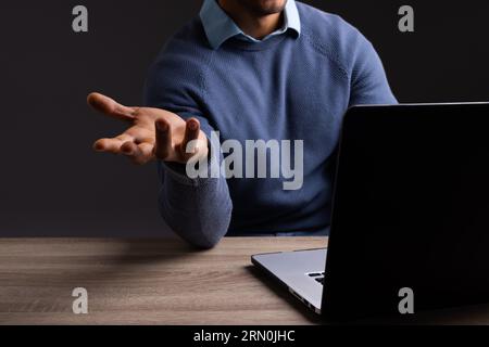 Birassischer Geschäftsmann, der Laptop benutzt und mit Kopierraum auf schwarzem Hintergrund zeigt Stockfoto