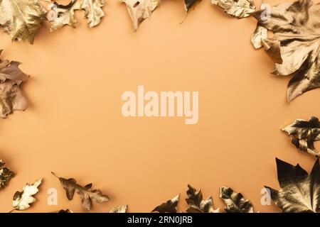 Metallisch-goldene Herbstblätter auf orangefarbenem Hintergrund Stockfoto