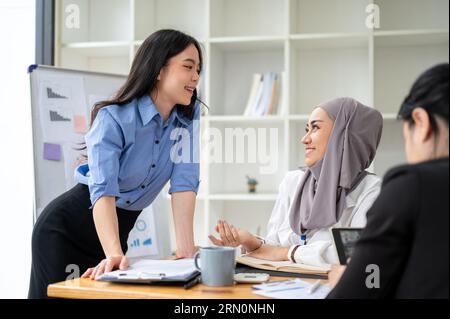 Eine schöne junge asiatische Geschäftsfrau diskutiert während des Treffens Ideen und arbeitet mit ihren verschiedenen Kollegen an einem Brainstorming für ein neues Projekt. Stockfoto