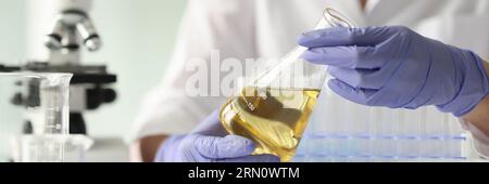 Eine Wissenschaftlerin, die eine Probe mit gelber Flüssigkeit hält Stockfoto