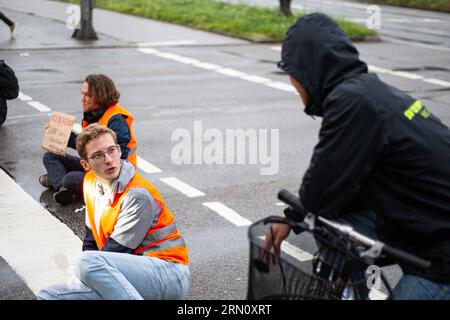 München, Deutschland. 29. August 2023. Am 29. August blockierten 2023 Aktivisten der letzten Generation mehrere Straßen in München. Die LastGen sieht die bayerischen Politiker als schlimmste Klimapolitik-Blockierer. Ferner fordert die letzte Generation eine Geschwindigkeitsbegrenzung von 100 km/h auf Autobahnen, die Einführung eines neun-Euro-Tickets und einen Rat der Klimagesellschaft. (Foto: Alexander Pohl/SIPA USA) Credit: SIPA USA/Alamy Live News Stockfoto