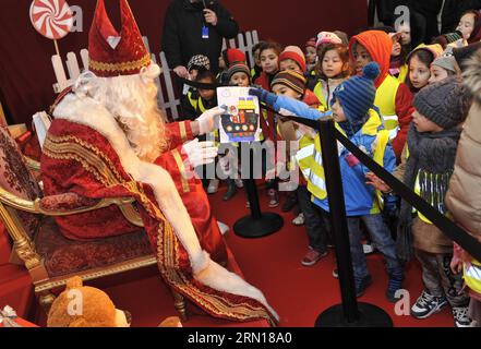 (141205) -- BRÜSSEL, 5. Dezember 2014 -- ein Akteur, der als Saint Nicolas verkleidet ist, erhält ein Gemälde von einem Jungen während des Saint Nicolas Festivals in Brüssel, Belgien, 5. Dezember 2014. Das St. Nicolas Festival kommt traditionell Mitte November oder dezember jedes Jahr in den Niederlanden und Belgien an. Auf seinem Pferd, mit seinem hilfsbereiten Assistenten Black Pete, wird er traditionell von Kindern begrüßt, die traditionelle Lieder des Heiligen Nikolaus singen und jubeln. BELGIEN-BRÜSSEL-SAINT NICOLAS FESTIVAL YexPingfan PUBLICATIONxNOTxINxCHN Brüssel DEC 5 2014 an Acotor gekleidet als Saint Nicolas Re Stockfoto