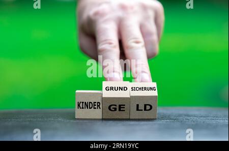 Hand dreht Holzwürfel und ändert den deutschen Ausdruck Kindergeld in Kindergrundsicherung. Symbol für t Stockfoto