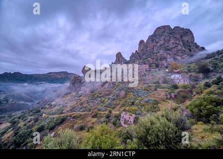Das Dorf Pentedattilo, das 1784 durch ein Erdbeben beschädigt wurde, und eine Geisterstadt, heute auf dem Monte Calvario, umgeben von Nebel. Stockfoto