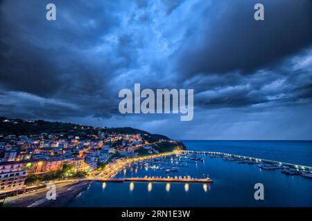 Luftaufnahme des Yachthafens und der Häuser der Stadt Agropoli, nachts beleuchtet, Sturmwolken in der Ferne. Stockfoto