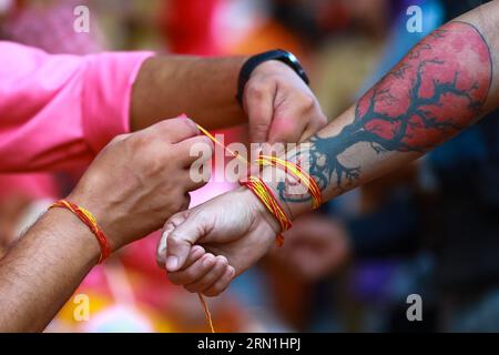 Kathmandu, Nepal. August 2023 31. Ein hinduistischer Priester bindet während des Janai Purnima Festivals einen heiligen Faden an eine Hand des Menschen. Janai Purnima, auch bekannt als das Sacred Thread Festival oder Rakshya Bandhan Festival, führen Hindus, insbesondere die Brahmans und Chettris, ihren jährlichen Wechsel von Janai auf, heilige Fäden, die über die Brust getragen oder um das Handgelenk gebunden und von Mantras gereinigt werden. Das Gewinde ist ein Symbol für Schutz. Quelle: SOPA Images Limited/Alamy Live News Stockfoto