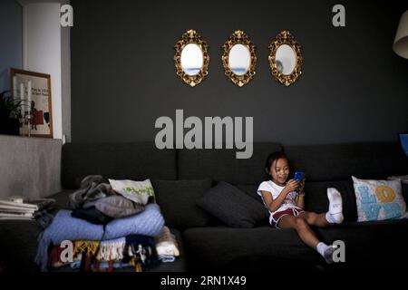 (150123) -- BARCELONA, 23. Januar 2015 -- Jana spielt am 20. Oktober 2014 in ihrem Haus in Barcelona, Spanien, Handy. Jana ist ein 8-jähriges Kind aus China. Im Alter von anderthalb Jahren wurde sie von einem spanischen Paar, Andreu und Thais adoptiert und zog nach Barcelona. Vor einem Jahr beschloss Jana, dem lokalen Team von Castellers de Sants beizutreten. Derzeit ist Jana der Star des Teams. Sie ist diejenige, die die Spitze des menschlichen Turms besteigt. SPANIEN-BARCELONA-CASTELLERS PauxBarrena PUBLICATIONxNOTxINxCHN Barcelona 23. Januar 2015 Jana SPIELT AM 20. Oktober in ihrem Haus in Barcelona Spanien Handy Stockfoto