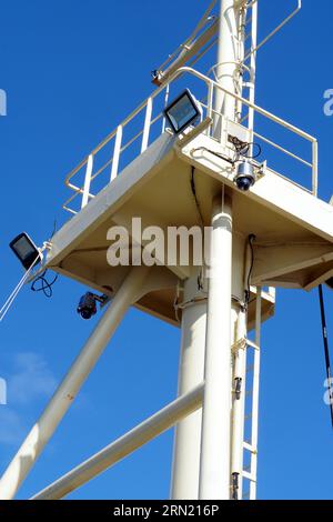 Vorwärtsmast des Schiffes mit Leiter und Plattform, wo sich CCTV-Überwachungskamera und LED-Lichtprojektoren befinden. Stockfoto