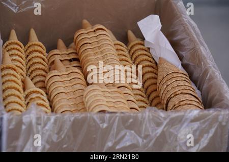 Stapel verschiedener Arten von Eiswaffelkegeln, die in einer Box platziert und mit einer Plastikfolie geschützt sind. Stockfoto