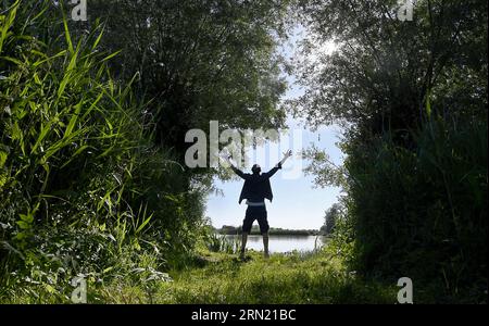 Biosphärenreservat „Marais Audomarois“ in Clairmarais (Nordfrankreich): Silhouette eines Mannes mit ausgestreckten Armen, mit Blick auf die Natur Stockfoto