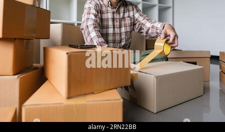 Konzept junger Mann Umzug Haus. Nahaufnahme Hand des Mannes Verwenden Sie Klebeband Versiegelung Karton Stockfoto