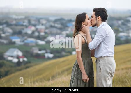 Mann und Frau stehen auf einem Hügel und küssen sich auf dem Hintergrund der Stadt Stockfoto
