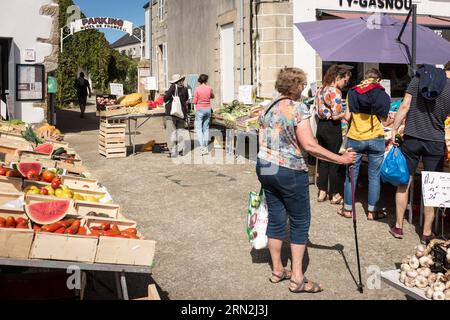 Kunden stöbern an einem Stand auf dem Wochenmarkt in Plougasnou, Britanny, Frankreich, nach festlichem Gemüse. Stockfoto