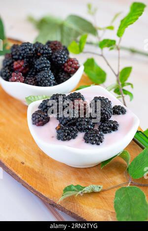 Wilde Beeren auf natürlichem Holzbrett mit cremigem Joghurt Stockfoto