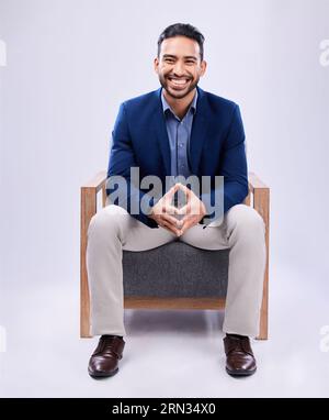 Porträt, Lächeln und Geschäftsmann auf Stuhl im Studio isoliert auf einem weißen Hintergrund Mockup Raum. Rechtsanwalt, glücklicher und zuversichtlicher Anwalt Stockfoto